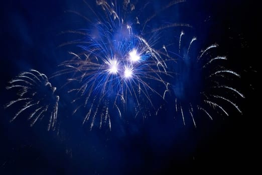 Blue colorful fireworks on the black sky background. Holiday celebration.