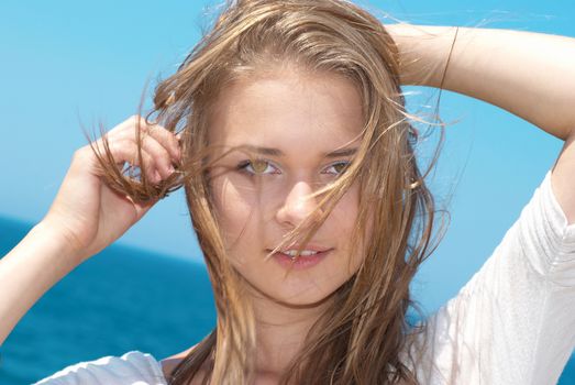 Beautiful blond girl with long hair against the blue sea