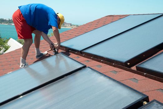 Worker solar water heating panels on the roof.