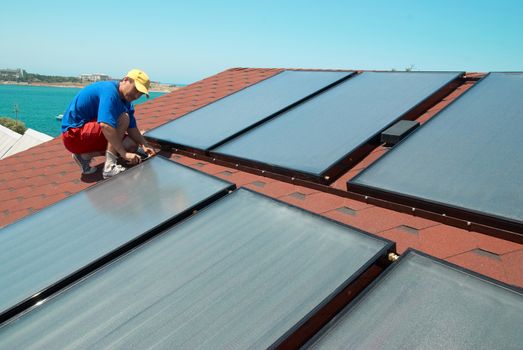 Worker solar water heating panels on the roof.