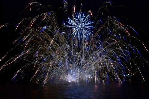 Blue colorful fireworks on the black sky background. Holiday celebration.