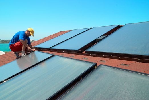 Worker solar water heating panels on the roof.