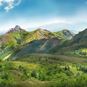 Green mountains covered with forest on the blue sky background. Panorama