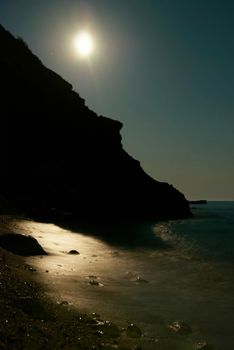 Moon night on the sea with waves and rocks.