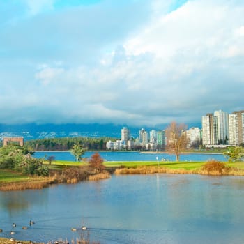 Green park near sea front with skyscrapers on the background. Vancouver, Canada.