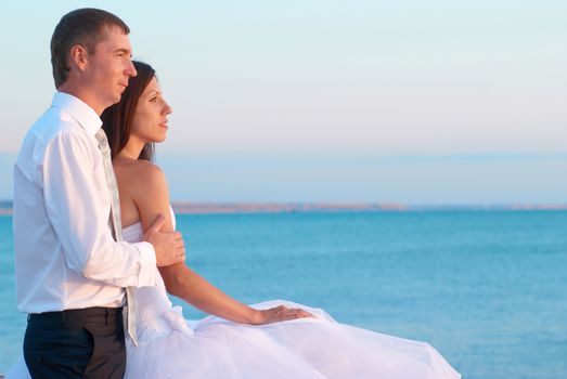 Beautiful wedding couple- bride and groom hugging at the beach. Just married