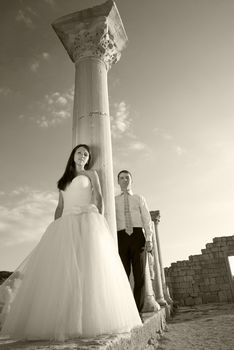 Beautiful wedding couple- bride and groom near greece column in the ancient city. Black and white, sepia