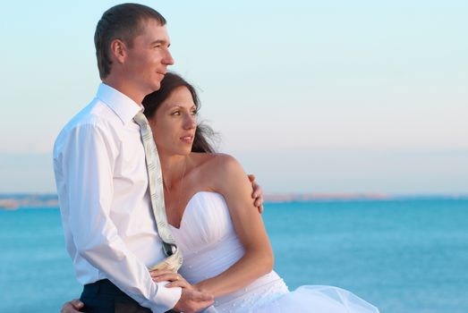 Beautiful wedding couple- bride and groom hugging at the beach. Just married