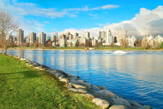 Green park near sea front with skyscrapers on the background. Vancouver, Canada.