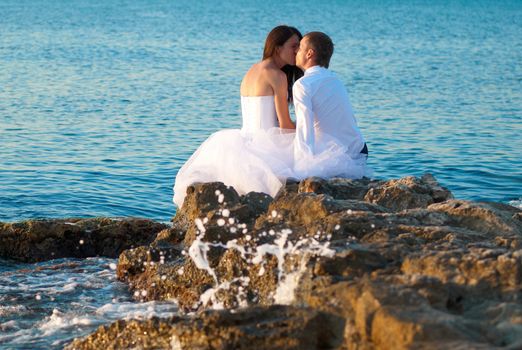 Beautiful wedding couple- bride and groom kissing at the beach. Just married