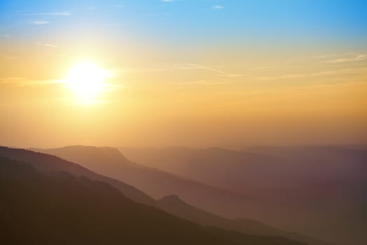 Beautiful sunset at the mountains. Colorful landscape with sun and blue sky