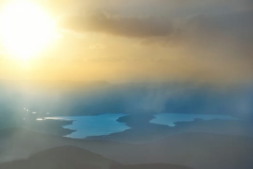 Sunset above the lake. Landscape with hills, clouds and sky.