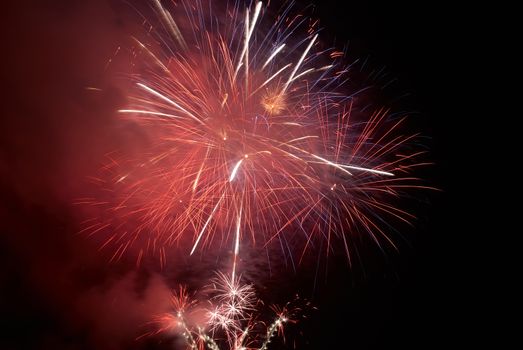 Red colorful holiday fireworks on the black sky background.