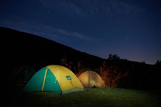 Illuminated yellow camping tent under stars at night