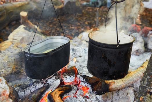 Boiling water in two pots above the fire.