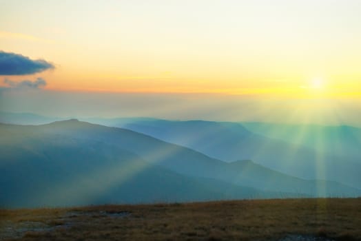 Beautiful sunset at the mountains. Colorful landscape with sun and blue sky