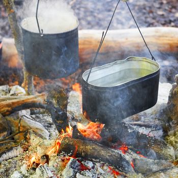 Boiling water in two pots above the fire.