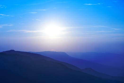 Beautiful sunset at the mountains. Colorful landscape with sun and blue sky