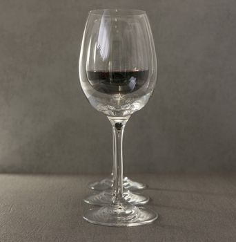 three wine glasses with red wine on dark gray background