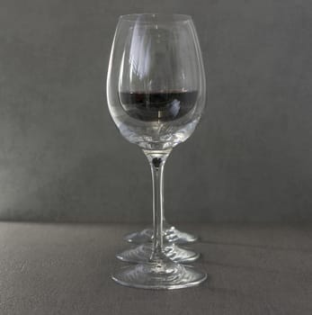 three wine glasses with red wine on dark gray background