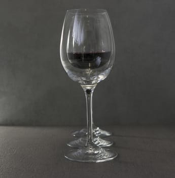 three wine glasses with red wine on dark gray background
