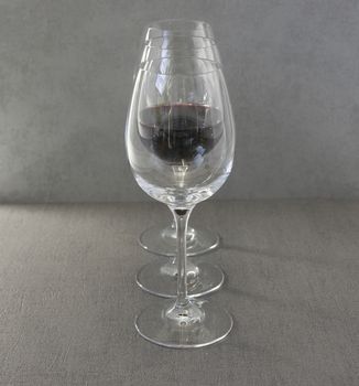 three glasses with one filled with red wine