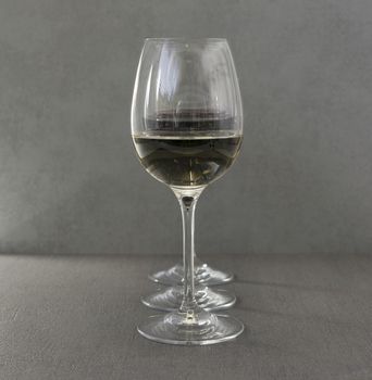 three glasses one with white and two with nred wine in arow