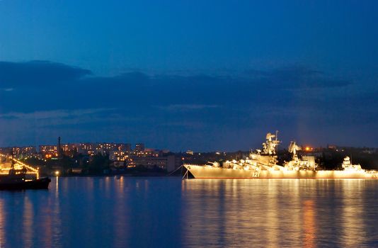 Russial illuminated warship in the evening bay.