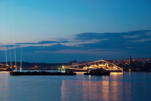 Russial illuminated warship in the evening bay.