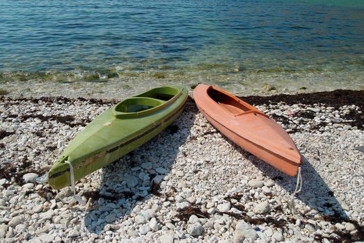 Two colour kayaks on the beach.