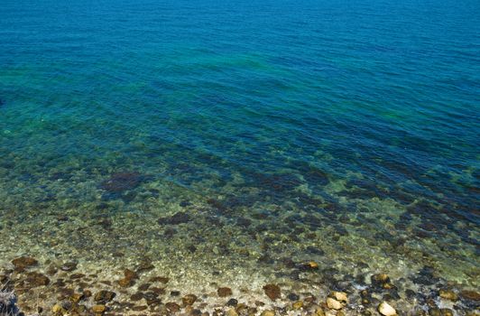 A coast with stones and blue ocean water.