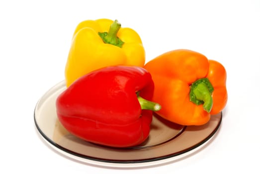 Three colored paprika on the plate on white background.