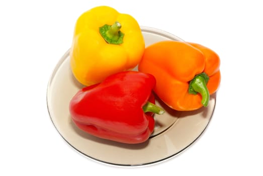 Three colored paprika on the plate on white background.