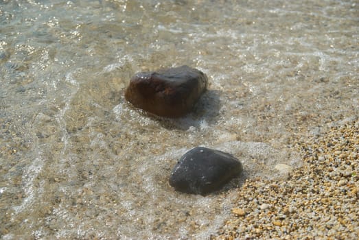 Rocks in the waves and sea foam.