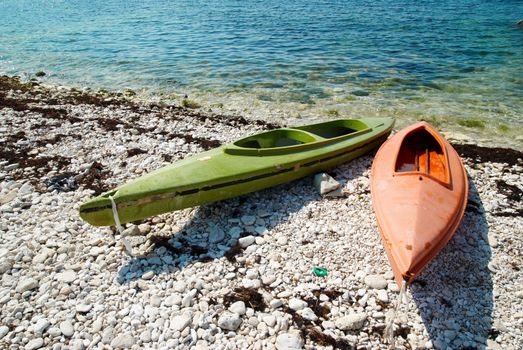 Two colour kayaks on the beach.