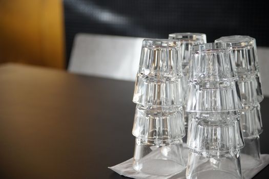 Clean drinking glasses stacked on a black table in a cafe.