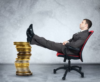 Businessman sitting on chair and gold coins on grey background