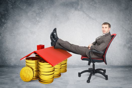 Businessman sitting on chair with coins and roof and legs up isolated on white background