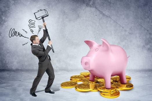 Businessman with hammer and white piggy bank with coins on grey wall background
