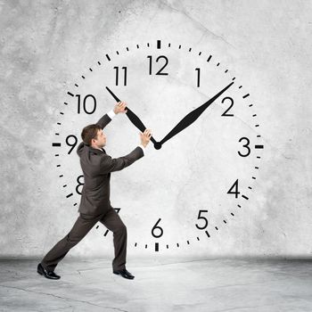 Businessman holding clock hand on grey wall backgound, rear view