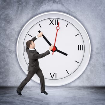 Businessman holding clock hand on grey wall backgound, side view