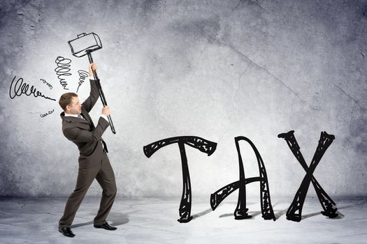 Businessman with hammer and word tax on grey wall background