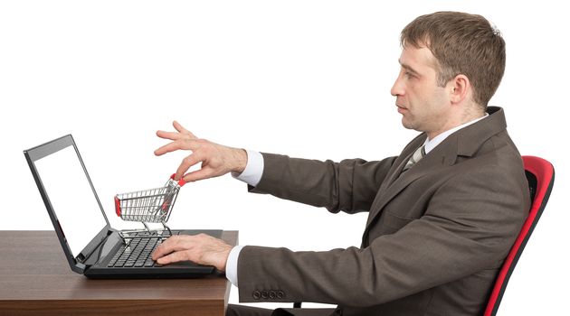 Businessman giving shopping cart to laptop isolated on white background, side view