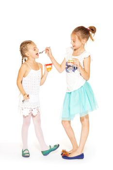 Beautiful little girls in white dress eating jelly