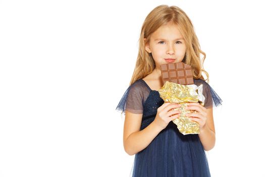 Beautiful blonde girl in a blue dress with curls eating a chocolate