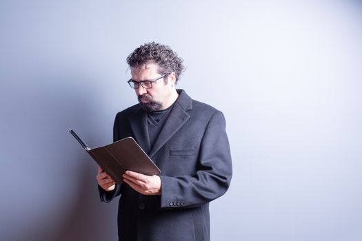 Waist Up of Business Man Wearing Suit Jacket and Eyeglasses Looking Serious While Reading Computer Tablet in Studio with Gray Background and Copy Space