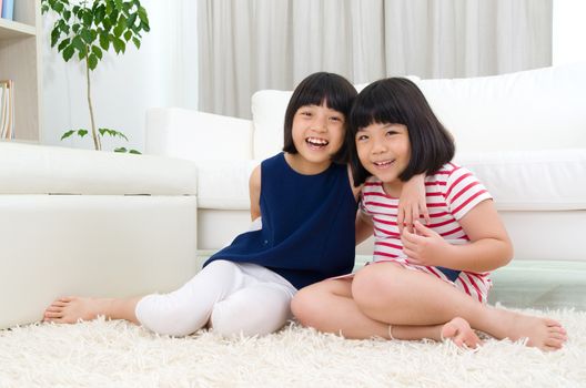 Asian sisters sitting on the floor