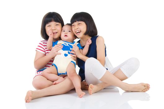 Asian sisters playing with their brother on the floor