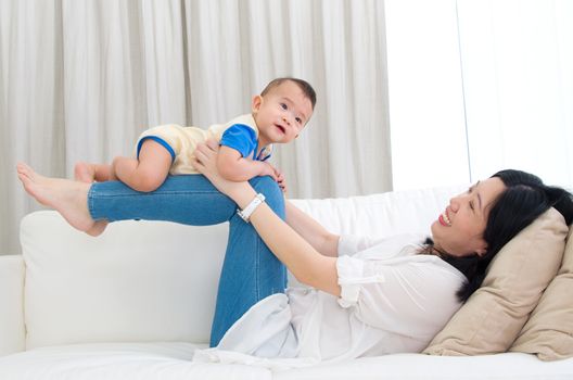 Asian mother lifting up her baby with legs