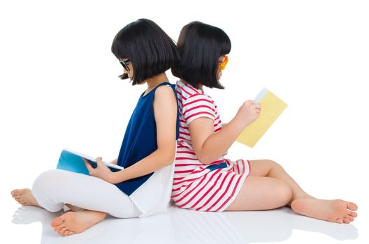 Asian girls wearing spectacles sitting on the floor with books